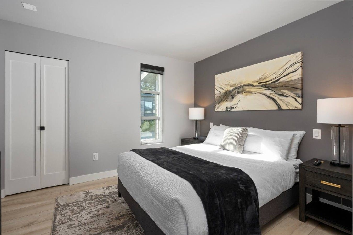 A bedroom with a bed, bedside lamps, a window, and a door.