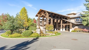 A lodge with a wooden exterior, a covered entrance, and a landscaped driveway. - Seaside 2 bdrm Townhome (Parksville)