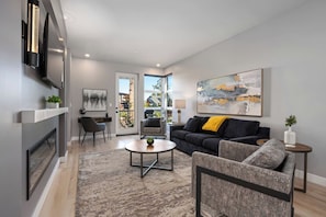 A modern living room with a fireplace, a sofa, a coffee table, and a large abstract painting.
