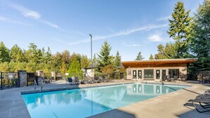 Une piscine avec des chaises longues et un bâtiment doté d’un toit en bois.