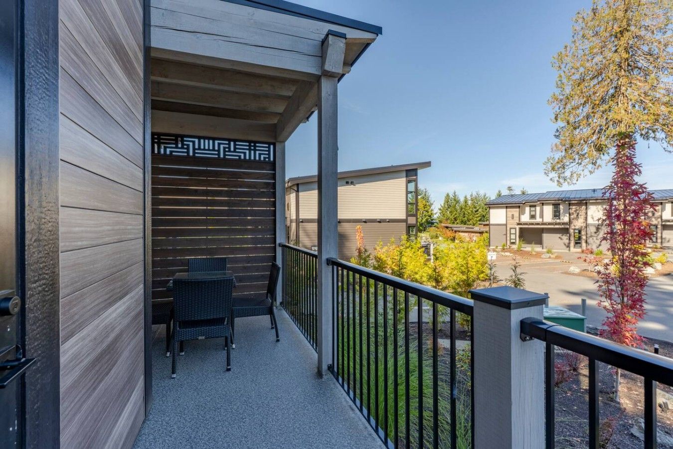 Un balcon avec une table et des chaises, un mur décoré de motifs et une vue sur d’autres immeubles et des arbres.