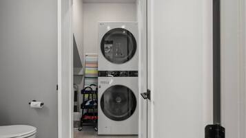 Een wasserette met twee gestapelde wasmachines en een klein opslagruimte met planken.