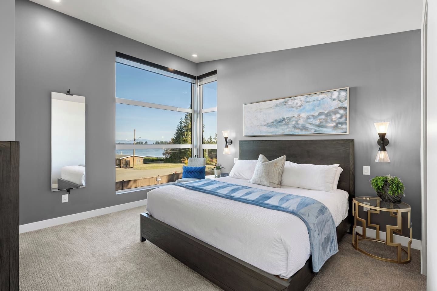 Une chambre à coucher moderne avec un grand lit, une vue sur l’extérieur et un tableau accroché au mur.