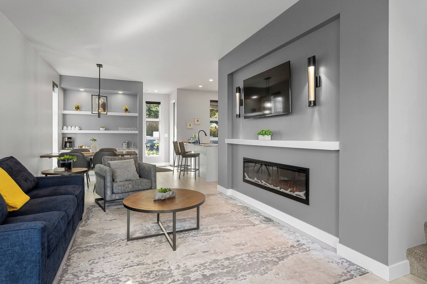 Un salon moderne avec une cheminée, un canapé, une table basse et un téléviseur fixé au mur.