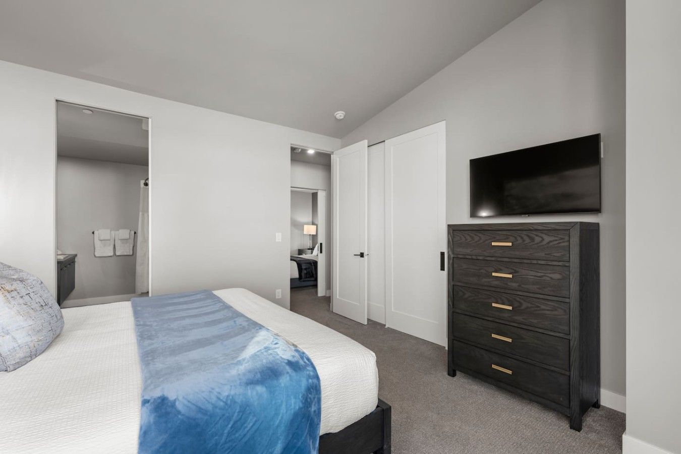 Een slaapkamer met een bed, een kaptafel, een televisie en een badkamer die door een open deur zichtbaar is.