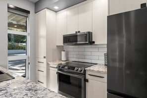 A modern kitchen with a stainless steel refrigerator, a microwave, a gas stove, and a built-in oven. - Seaview end unit monthly rates (Parksville)