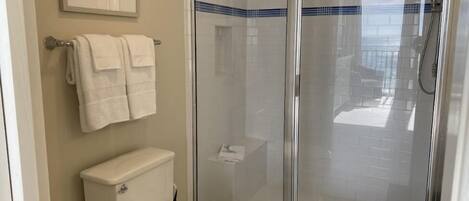 Un baño con inodoro, ducha con cerramiento de vidrio y un cuadro en la pared.