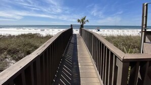 A wooden boardwalk leading to a beach with a clear sky.