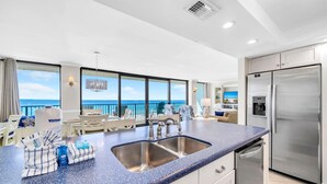 A modern kitchen with a large island, stainless steel appliances, and a view of the ocean.