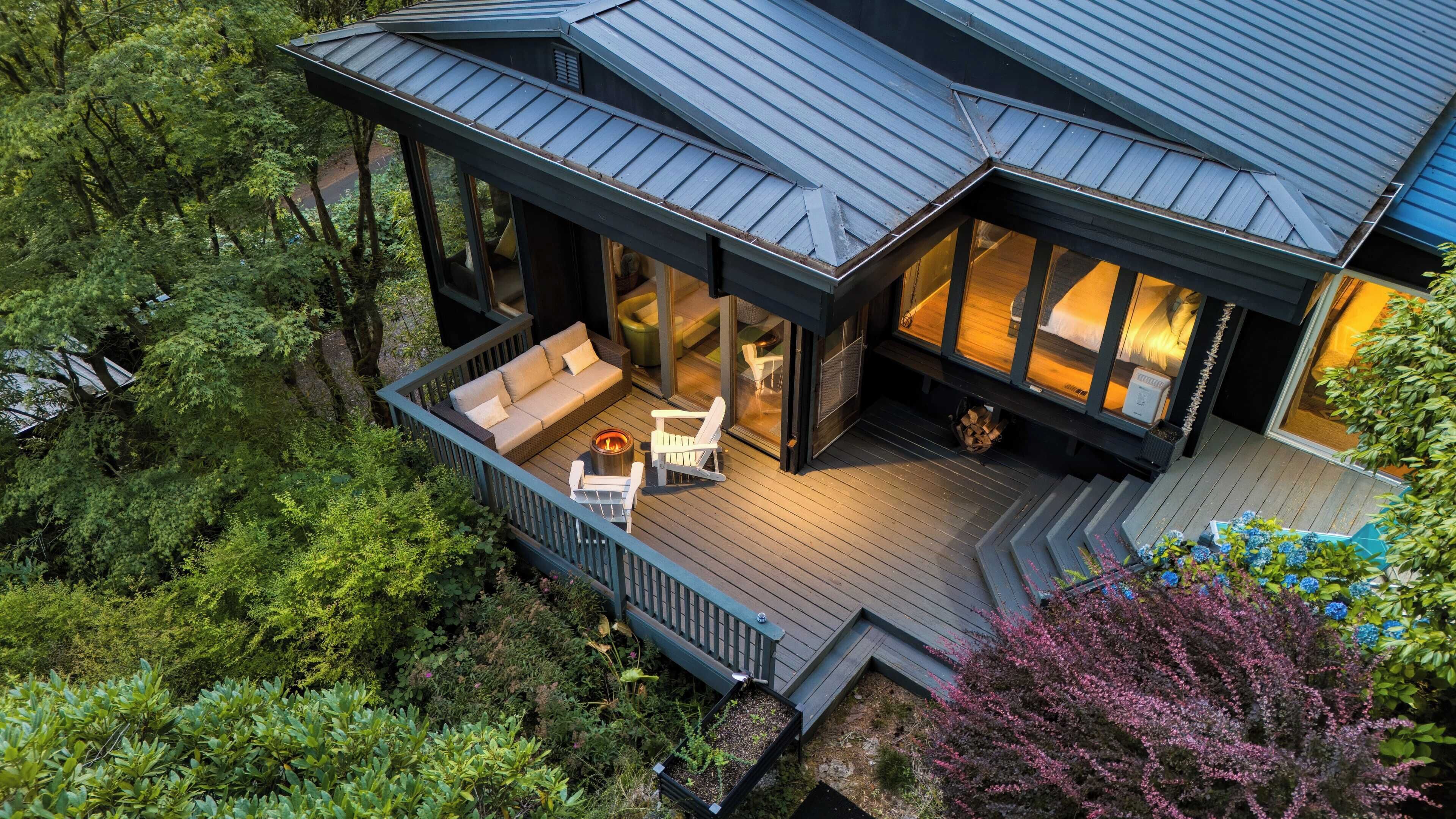 A modern house with a deck, a fire pit, and a sofa.