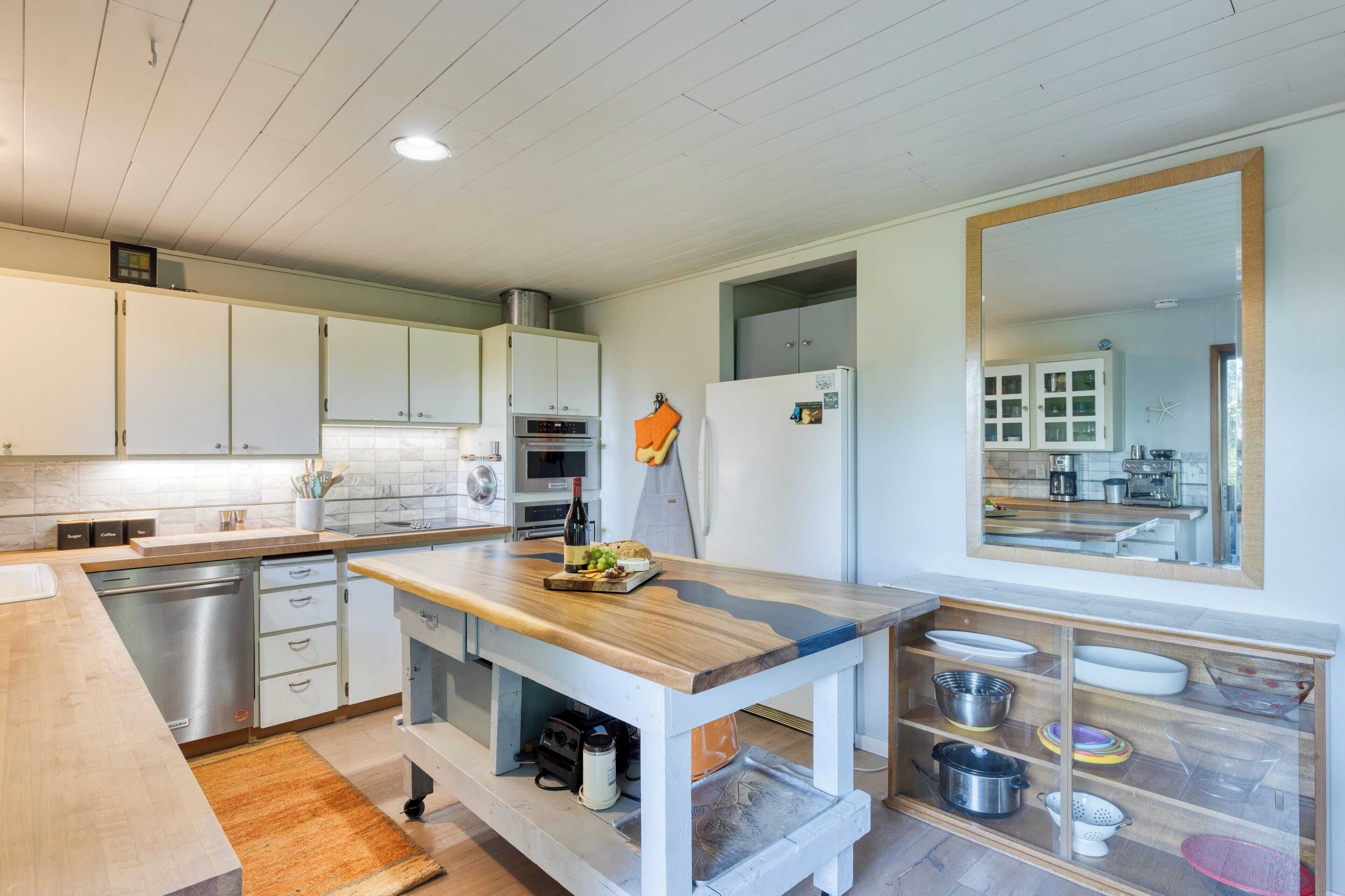 A modern kitchen with white cabinets, a wooden countertop, and a built-in oven.