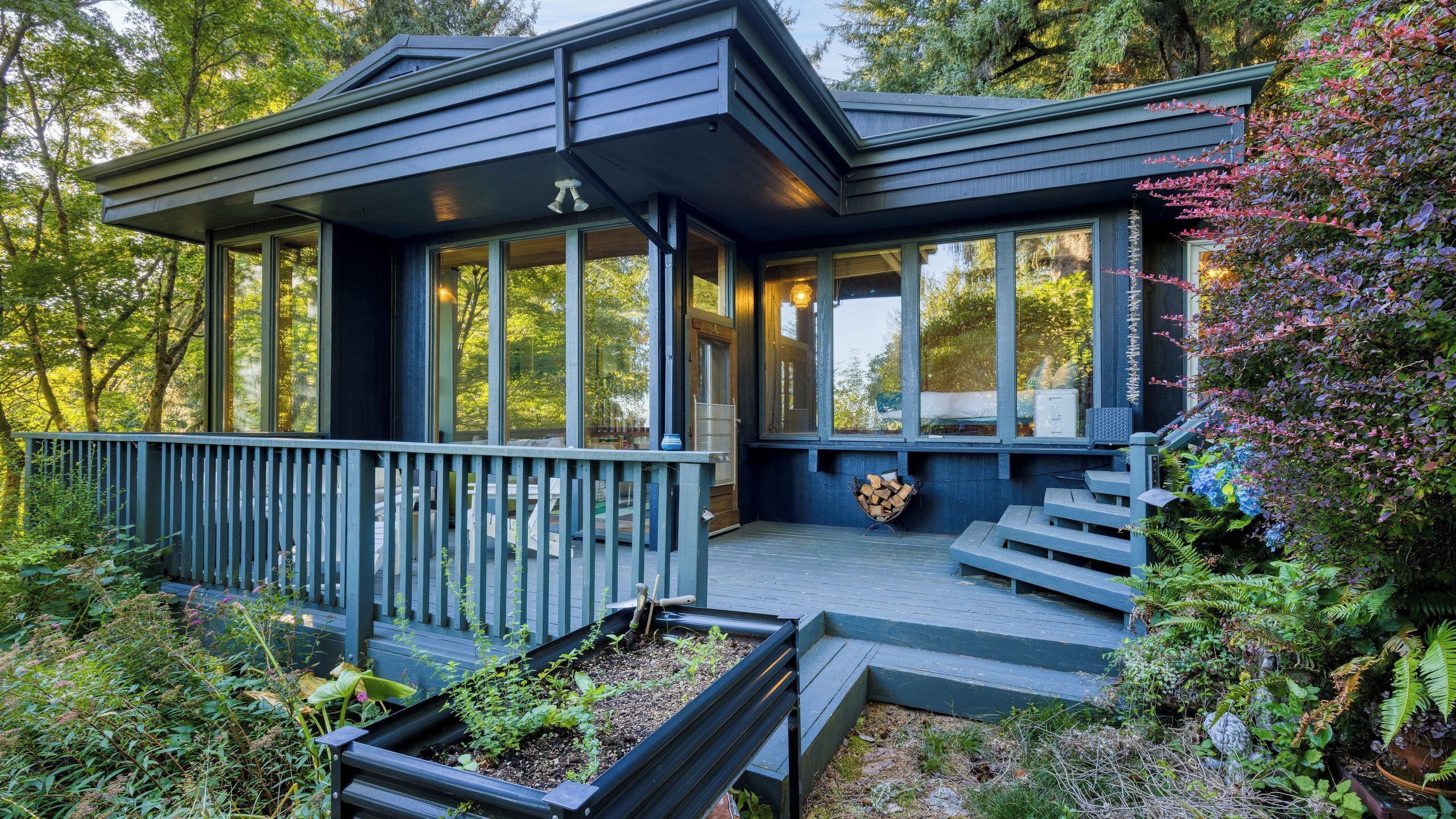 A modern house with a covered porch, large windows, and a wooden deck.