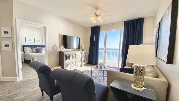 Une chambre d’hôtel avec un balcon, un canapé, une télévision et une lampe.