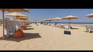 Una playa con hileras de sillas y sombrillas blancas, evocando un ambiente de resort.