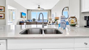 Una cocina moderna con una isla grande, pileta de acero inoxidable y un ventilador de techo.