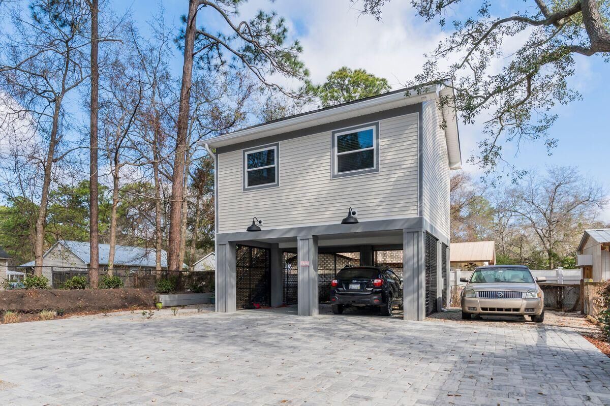Une maison à deux étages avec un garage, une allée et une voiture garée à l’intérieur.