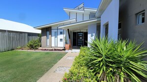 A modern two-story house with a front porch, a fenced backyard, and well-maintained landscaping.
