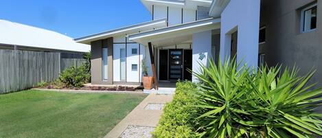 A modern two-story house with a front porch, a fenced backyard, and well-maintained landscaping.