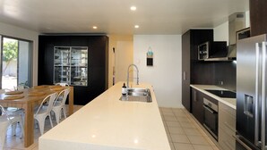 A modern kitchen with a central island, stainless steel appliances, and a dining area with a glass door pantry.