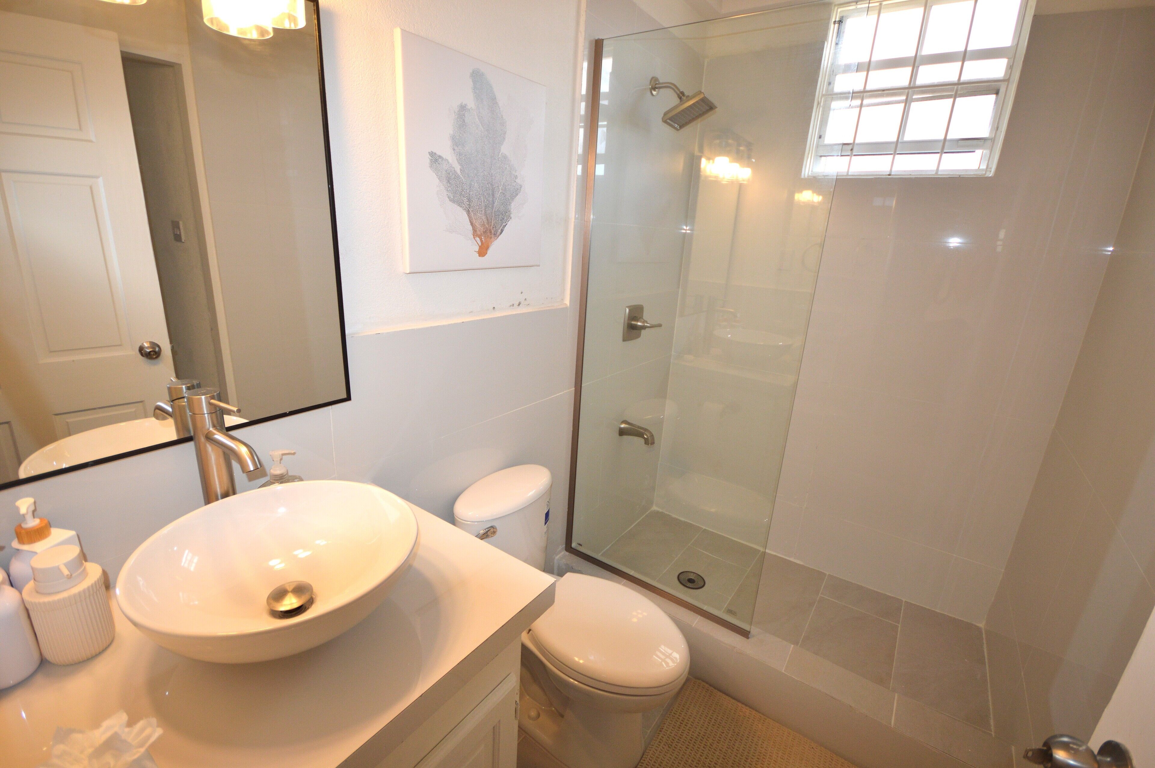 A bathroom with a white sink, toilet, and a glass-enclosed shower.