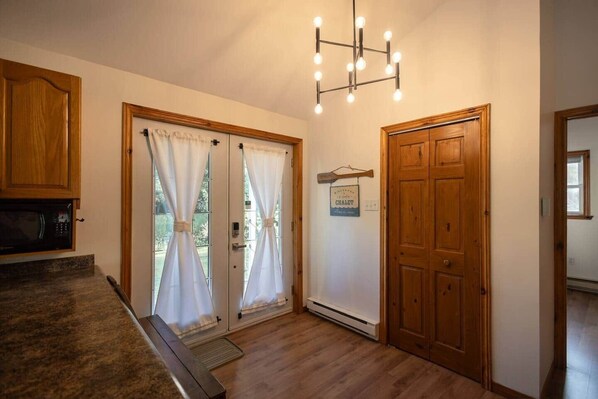 A kitchen with wooden cabinets, a microwave, and a chandelier. - Chalet Entre Lac et Rivière (Weedon)