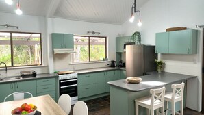 Eine moderne Küche mit grünen Schränken, einem Edelstahl-Kühlschrank und einem Essbereich mit Tisch und Stühlen.