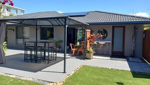 Ein Haus mit überdachter Terrasse, Essbereich und kleinem Garten.