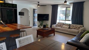 Ein modernes Wohnzimmer mit Essbereich aus Holz, einer Couch und einem Fernseher.