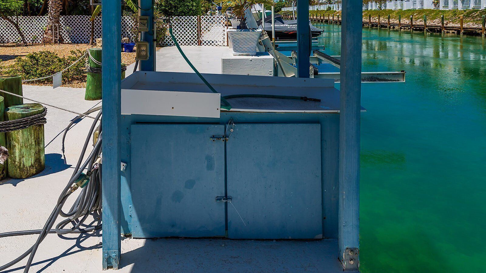 Una estructura metálica azul con una puerta, conectada a un muelle con barcos.