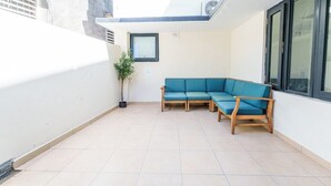 A small, enclosed patio area with a blue sofa and a potted plant.