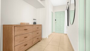 A hallway with a wooden dresser, a green door, and a wall-mounted mirror.