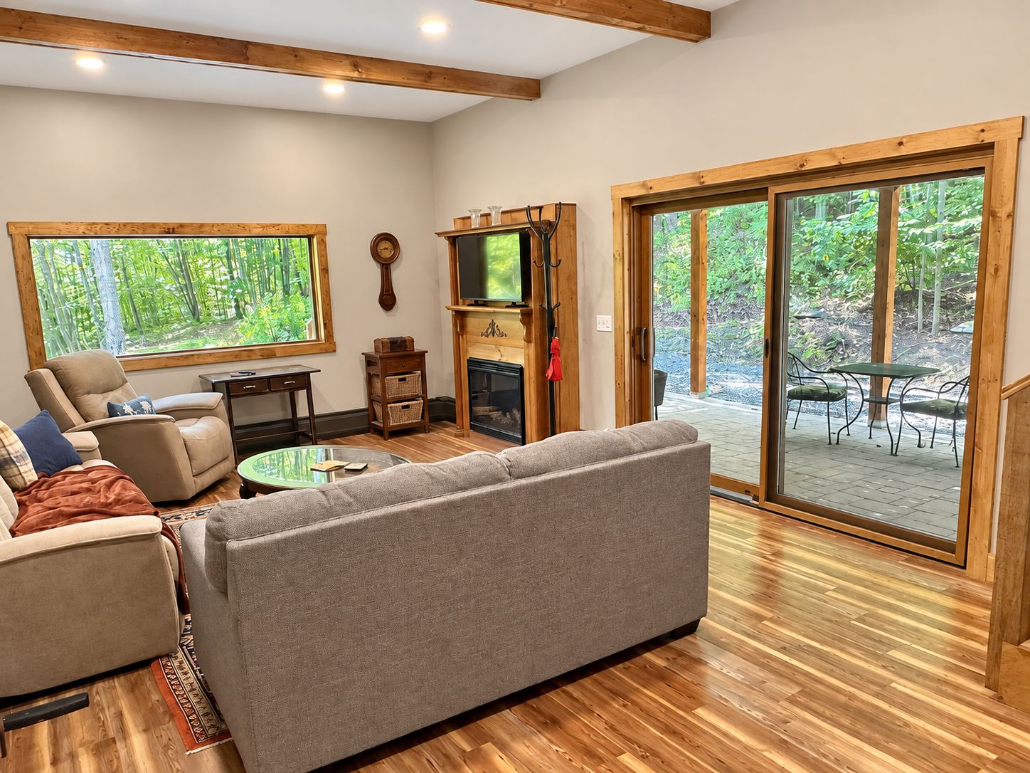 A cozy living room with a fireplace, comfortable seating, and large windows offering a view of the outdoors.