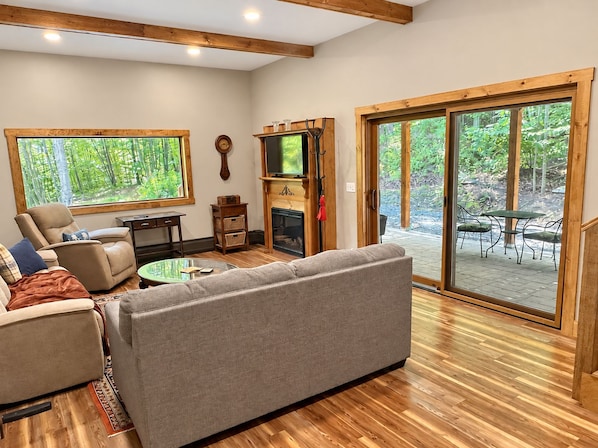 Una sala de estar acogedora con chimenea, asientos cómodos y ventanas amplias que ofrecen vistas al exterior.