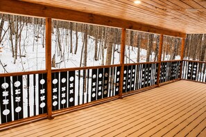 Eine Holzterrasse mit Blick auf einen verschneiten Wald.
