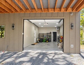 Eine geräumige Garage mit Betonboden, Holzbalken an der Decke und einer Tür zu einem weiteren Raum.