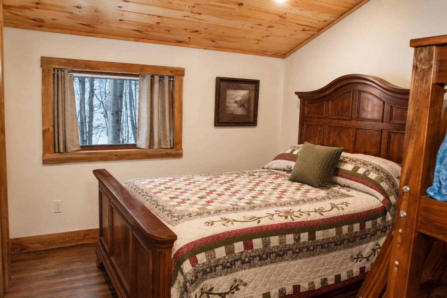 Un dormitorio con cama de madera, ventana con cortinas, un cuadro enmarcado en la pared y un armario de madera.