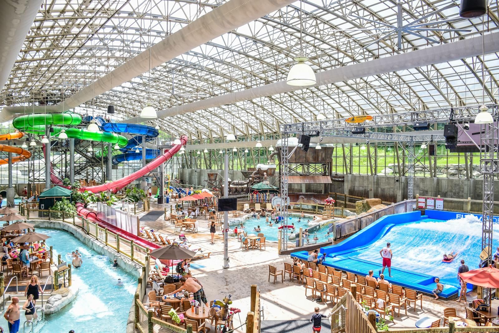 Un parc aquatique intérieur doté de plusieurs piscines, de toboggans et d’un espace couvert avec des sièges.