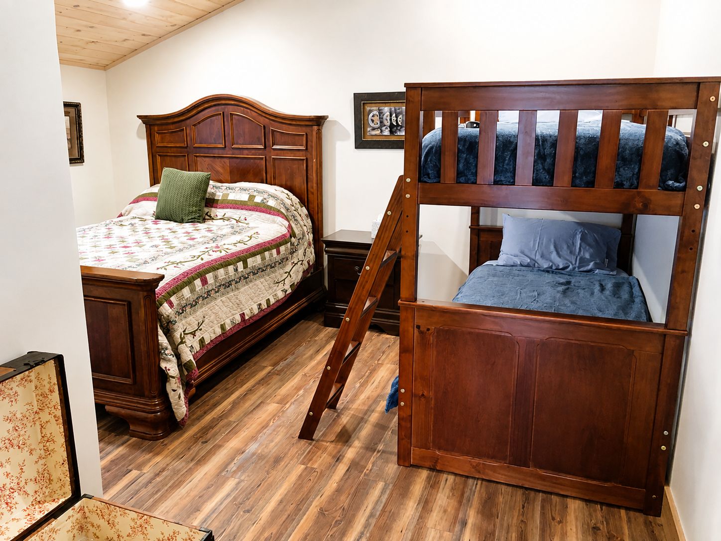 Une chambre avec deux lits en bois, dont l’un est un lit superposé, et une échelle en bois.