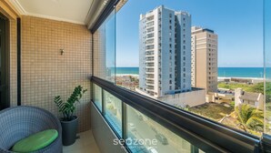 A balcony with a view of a beach and high-rise buildings.