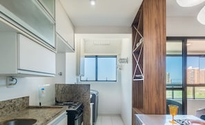 A compact kitchen with a granite countertop, a built-in stove, and a window providing a view of the city. - Apart With Sea View 250m From the Beach Ais0305 (Salvador)