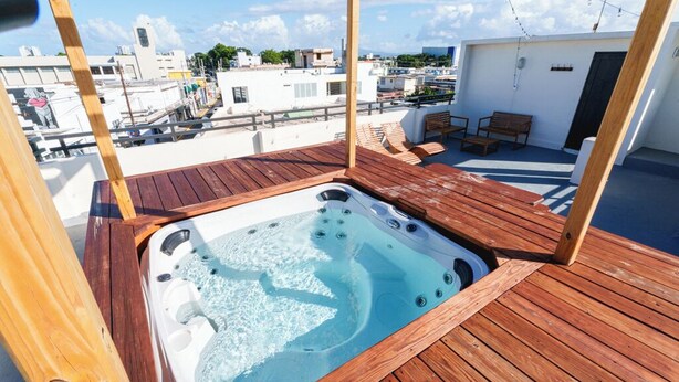 Terraza en la azotea con jacuzzi, piso de madera y zona de estar.