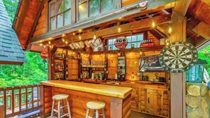 A rustic bar area with wooden furniture, a dartboard, and various signs including "Jack Daniel's".