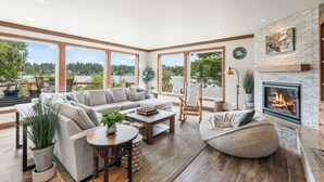 A spacious living room with a fireplace, large windows, and a view of the outdoors.