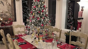 Een eetkamer met een kerstboom, rode tafelkleden en feestelijke decoraties.