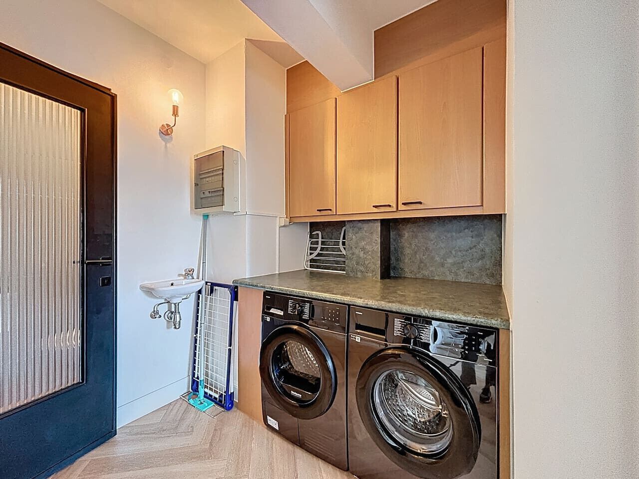 A compact laundry room with a washing machine, dryer, and a sink.
