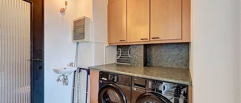A compact laundry room with a washing machine, dryer, and a sink.
