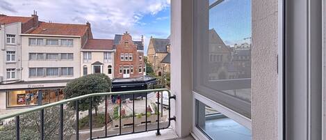 A balcony with a view of a street, buildings, and a clear sky.