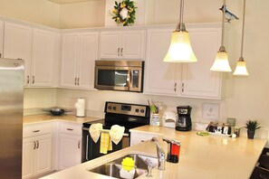 A modern kitchen with white cabinets, stainless steel appliances, a sink, and pendant lighting.