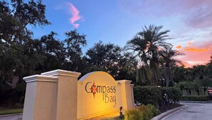 A sign for Compass Bay with a landscaped entrance and palm trees.