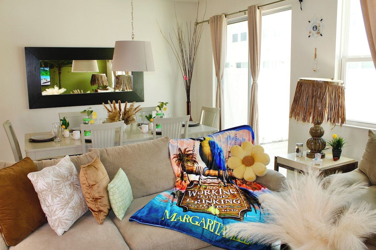 Un salon avec un canapé, une table basse, un téléviseur et une fenêtre avec des rideaux.